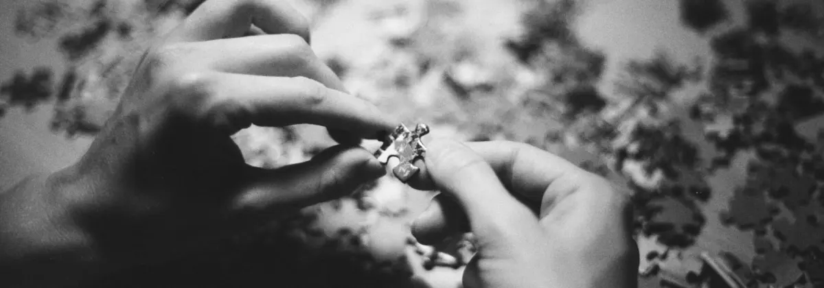 Two pairs of hands assembling puzzle pieces.